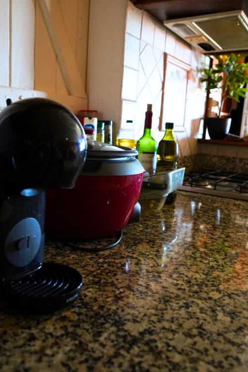 Cuisine du gîte R'marine439 à Sainte-Rose : plan de travail en granit, cafetière et bouteilles de vin