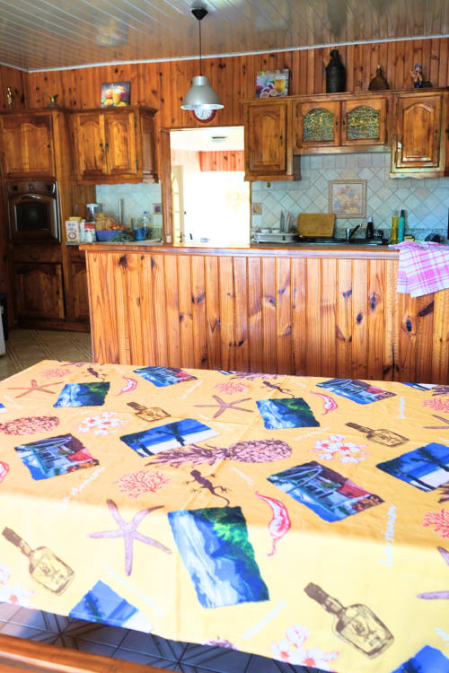 Table de salle à manger au style plage coloré dans la cuisine du gîte R'marine439, Gîte Sainte-Rose, avec cabinetrie en bois et design moderne