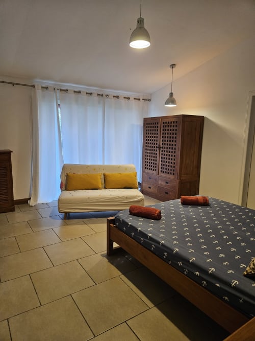 Chambre spacieuse à la villa R'marine439 à Sainte-Rose avec lit, canapé, armoire en bois et vue sur mer
