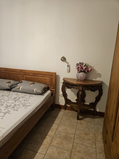 Chambre de la villa R'marine439 à Sainte Rose avec lit en bois, table de nuit décorée de fleurs roses et carrelage