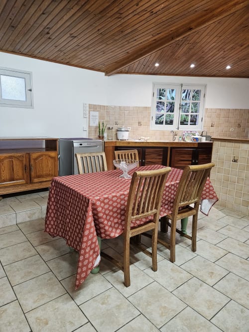 Salle à manger de la villa à R'marine439 à Sainte Rose avec table en bois, nappe à motifs rouges et cuisine