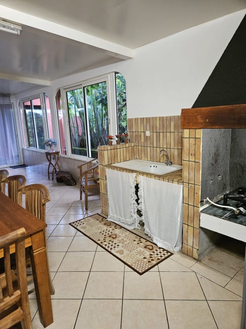 Cuisine spacieuse et coin repas à la Villa Cœur des laves chez R'marine439, Sainte-Rose avec mobilier en bois et vue sur mer