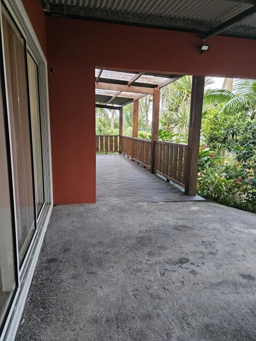 Véranda ouverte de la villa R'marine439 à Sainte-Rose avec vue sur jardin tropical et terrasse en bois