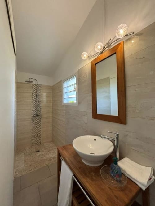 Salle de bains moderne à la villa R'marine439 à Sainte-Rose avec douche à l'italienne, lavabo rond, meuble en bois et éclairage décoratif