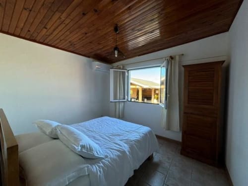 Chambre lumineuse avec literie bleue, plafond en bois et vue sur mer à la villa R'marine439 à Sainte-Rose