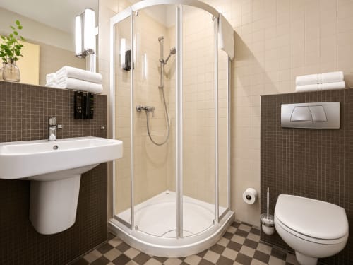 Salle de bain moderne de l'Hôtel De La Poste avec douche, lavabo, toilettes et carrelage aux teintes sombres