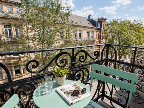 Balcon de l'Hôtel De La Poste avec chaises vertes, journal et vue sur la ville d'Esch-sur-Alzette