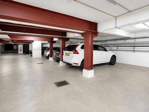 Parking souterrain de l'Hôtel De La Poste à Esch-sur-Alzette avec voitures blanches et colonnes de soutien rouges