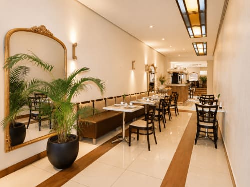 Élégante salle à manger de l'Hôtel De La Poste avec banquettes, chaises noires et plantes vertes à Esch-sur-Alzette