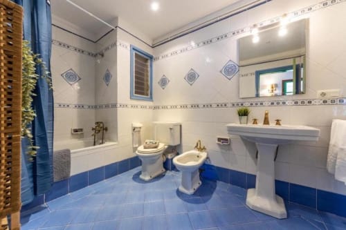 Modern blue and white bathroom with toilet, bidet, pedestal sink and shower in Salou apartment