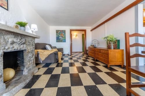 Spacious living room in Salou apartment with checkered floor, fireplace, wooden furniture, and plants