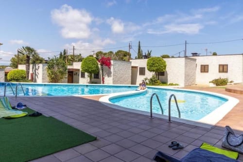 Twin swimming pools at Rentalaya apartment complex in Salou with white buildings and Mediterranean landscaping