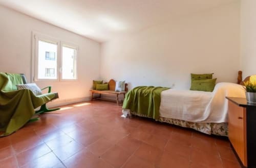 Spacious 2-bedroom apartment bedroom in Salou with terracotta tile flooring, twin beds with green bedding, and bright natural