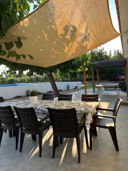Outdoor dining area at Rentalaya villa in Reus with shade sail, black chairs, patio table, and pool view
