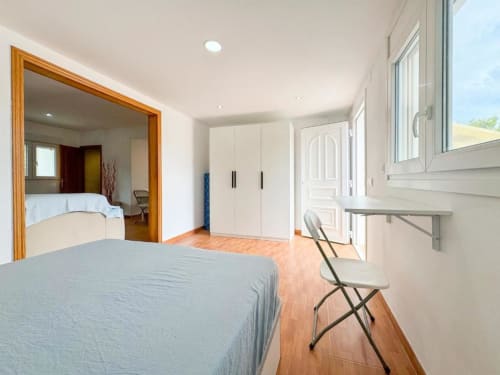 Spacious villa bedroom in Reus with wooden floors, blue bed, white wardrobe, garden view windows, and modern furnishings