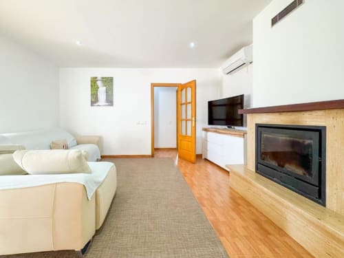 Spacious villa living room in Reus with fireplace, sofa, TV, and garden views
