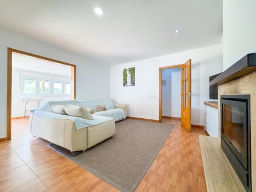 Spacious living room in Reus villa with cream sofa, fireplace, wooden doors, and garden views