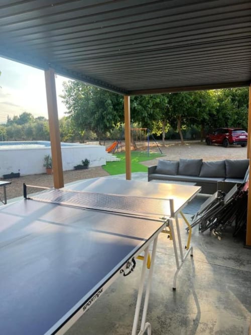 Covered patio with ping pong table, outdoor seating, barbecue, and pool view at Rentalaya villa in Reus