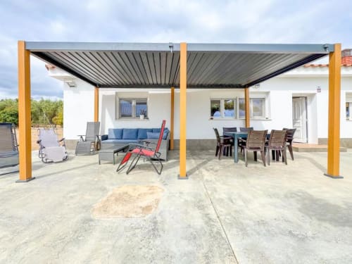 Modern villa patio in Reus with retractable pergola, outdoor dining table, seating area, and garden views