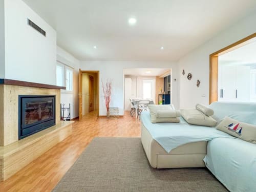 Spacious villa living area in Reus with fireplace, cream sofa, wooden floors, and garden views