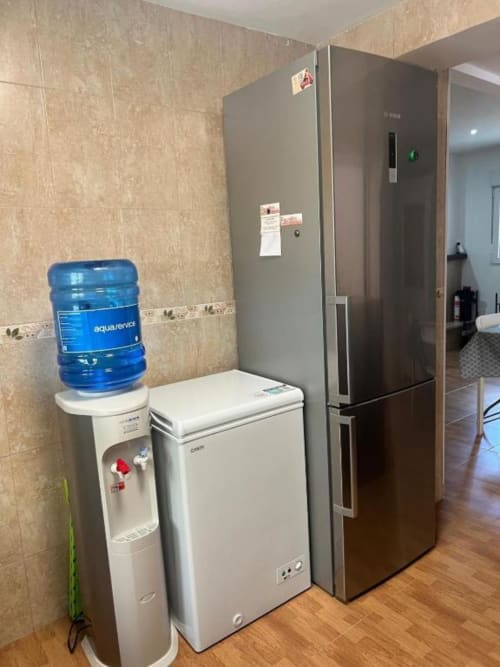 Kitchen area in Reus villa with refrigerator, water cooler, freezer, and modern appliances