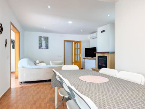 Modern villa dining area with kitchen in Reus, featuring dining table, living room sofa, fireplace, and garden views