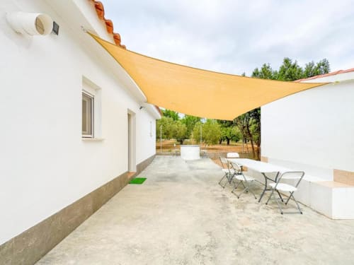 Villa patio with yellow sun shade, outdoor dining table, and garden views in Reus, Spain