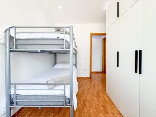 Modern bunk bed in white villa bedroom at Rentalaya, Reus with wooden flooring and wardrobe