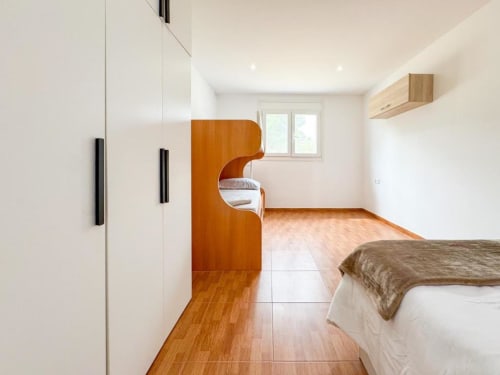 Modern villa bedroom in Reus with wooden furniture, white walls, natural light, and hardwood flooring