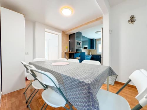 Modern villa dining area in Reus with kitchen, table for four, wooden floors, and contemporary blue cabinetry