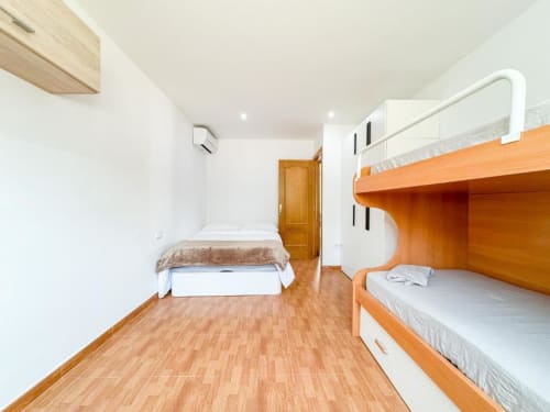 Bright villa bedroom with wooden bunk beds, single bed, and wooden flooring in Reus