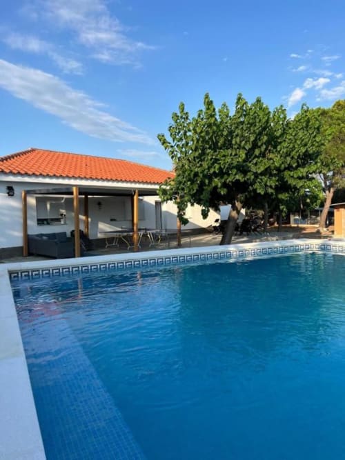 Modern villa with private pool, terrace, and garden view in Reus, featuring white building with orange roof and wooden