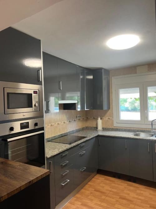 Modern kitchen in Reus villa with dark cabinetry, granite countertops, stainless steel appliances, and garden views