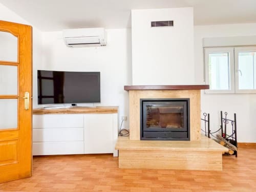 Modern villa living room with fireplace, flat-screen TV, and garden views in Reus