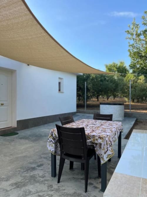 Outdoor dining area at Rentalaya villa in Reus with table, black chairs, and beige shade sail