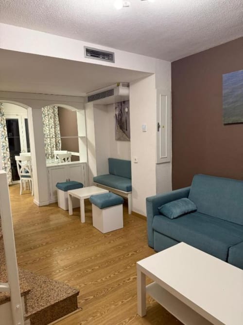 Modern apartment living area with teal sofas, white furniture, wooden flooring at Rentalaya in Peñíscola