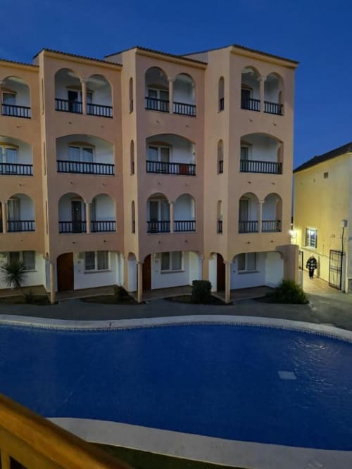 Peñíscola apartment building with pool view, balconies, and covered ground-level parking at Rentalaya