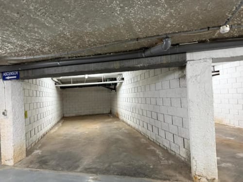Underground parking tunnel with white brick walls and black pipes at Rentalaya apartment complex in Peñíscola