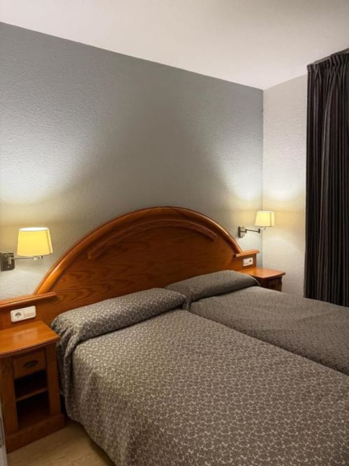 Modern bedroom in 2-bedroom apartment at Rentalaya, Peñíscola with wooden headboard, gray bedding, wall lamps, and dark