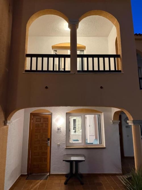 Peñíscola apartment exterior at night showing arched balconies, wooden door, and illuminated windows