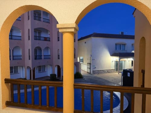 Terrace view of Rentalaya apartment in Peñíscola with arched opening overlooking pool area and Mediterranean-style buildings