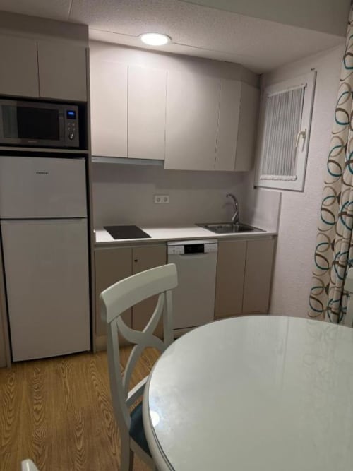 Modern apartment kitchen with stove, sink, refrigerator, and dining table in Peñíscola rental