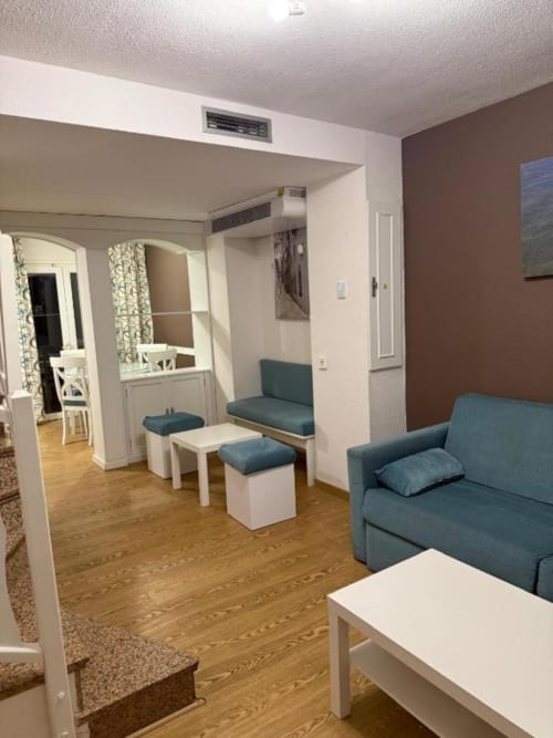 Spacious living area in Rentalaya's 2-bedroom apartment in Peñíscola with teal sofa, mirrored alcove, and modern furnishings
