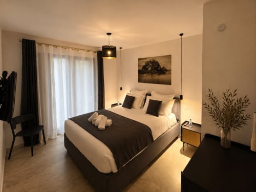 Chambre élégante aux Villas Vallée d'Asco, Corse avec lit queen, accents noirs, luminaires suspendus et mobilier moderne