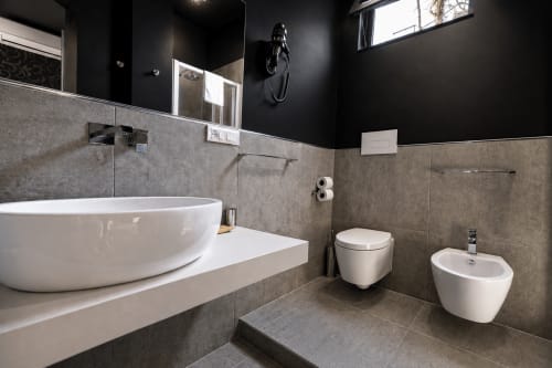 Bagno moderno in B&B Pellicano Guest House, Reggio Calabria, con lavabo bianco curvo, wc e bidet sospesi, grigio