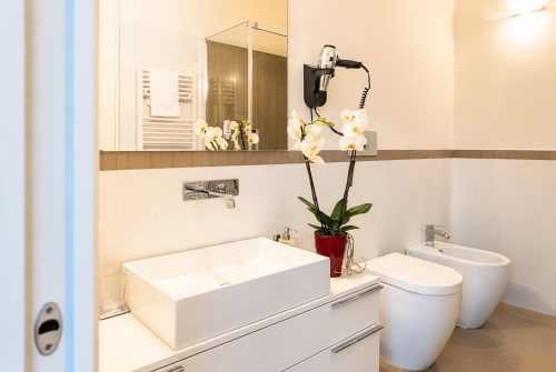 Bagno moderno presso B&B Pellicano a Reggio Calabria con lavabo rettangolare bianco, toilette, bidet, ampio specchio e finiture bianche