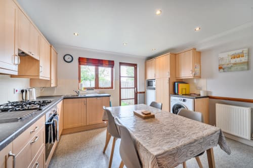 Sunflower Cottage kitchen with dining table, wooden cabinets, gas range, and garden views in Exeter