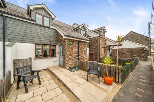 Sunflower Cottage garden view with patio seating, stone exterior, and fenced private back garden in Exeter
