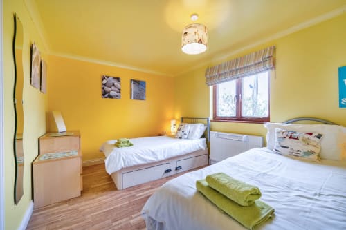 Bright yellow twin bedroom at 2 Doves Holiday Property cottage in Exeter with white bedding and garden views