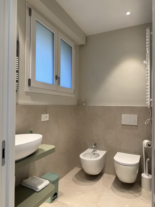Bagno moderno nell'appartamento La Casetta dei Ronchi a Marina di Massa, con sanitari bianchi e rivestimenti beige